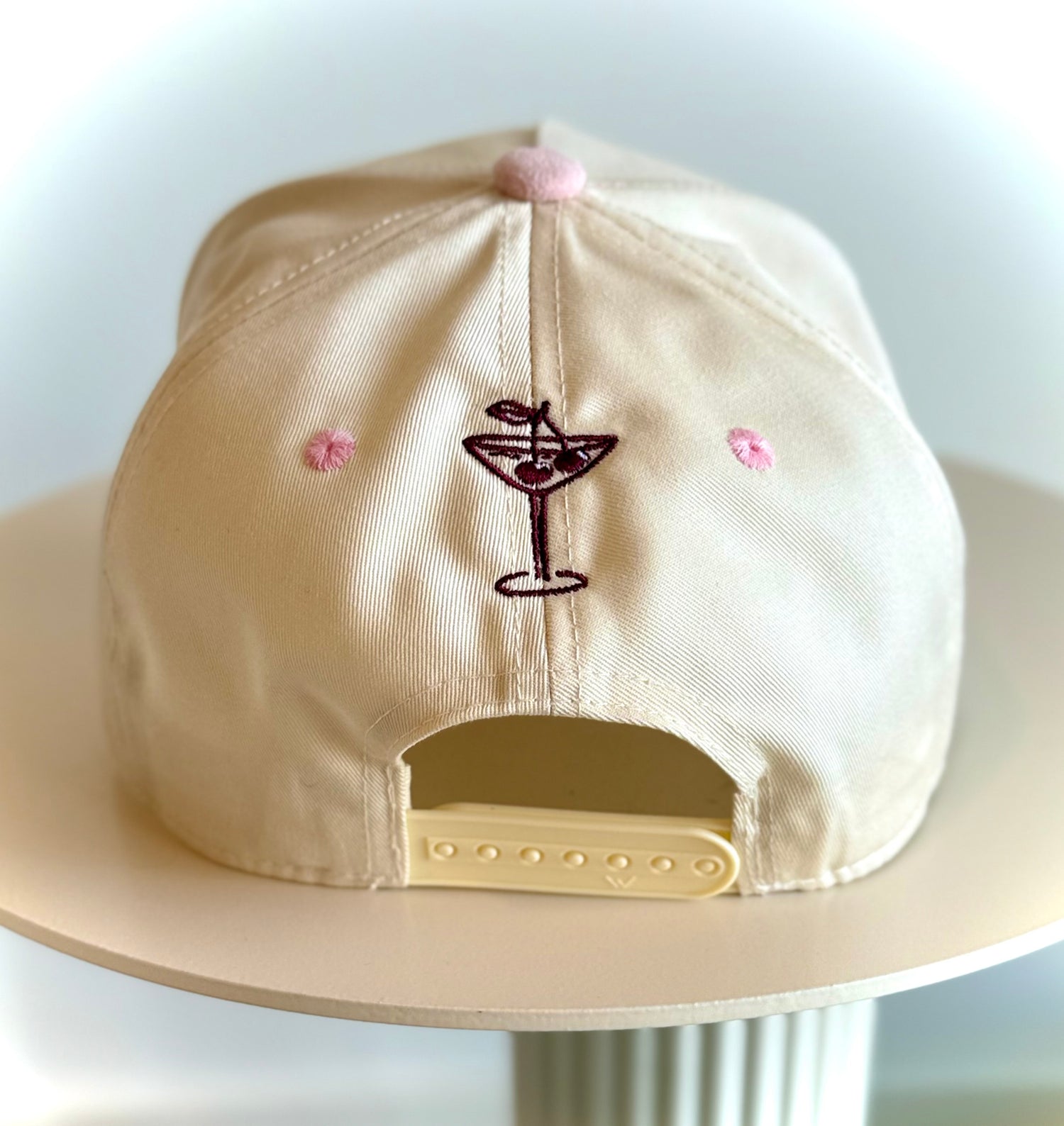 Beige cap with a cocktail glass design and pink flowers on a white background