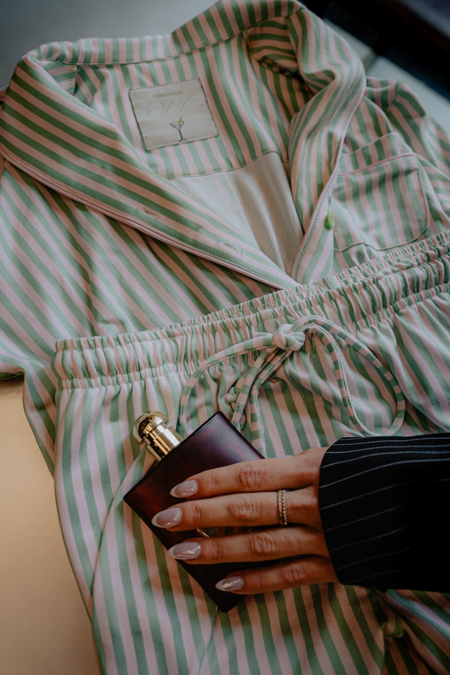 Person wearing a green and white striped robe holding a black clutch.