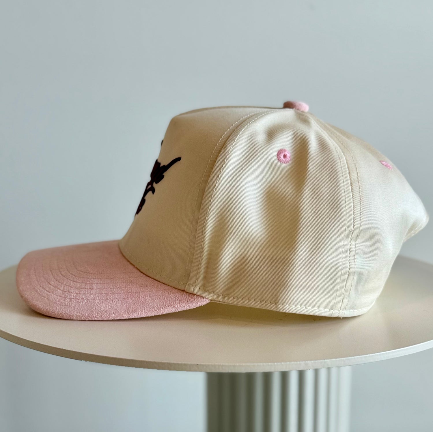 Beige and pink cap on a white surface with a light gray background
