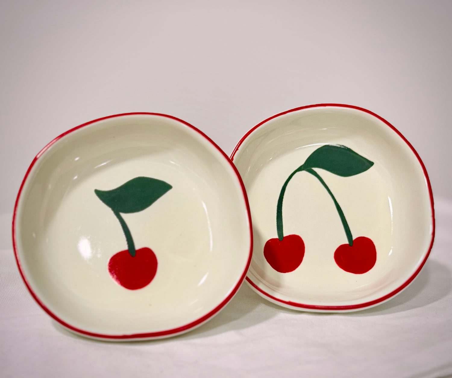 Two ceramic bowls with cherry designs on a white background