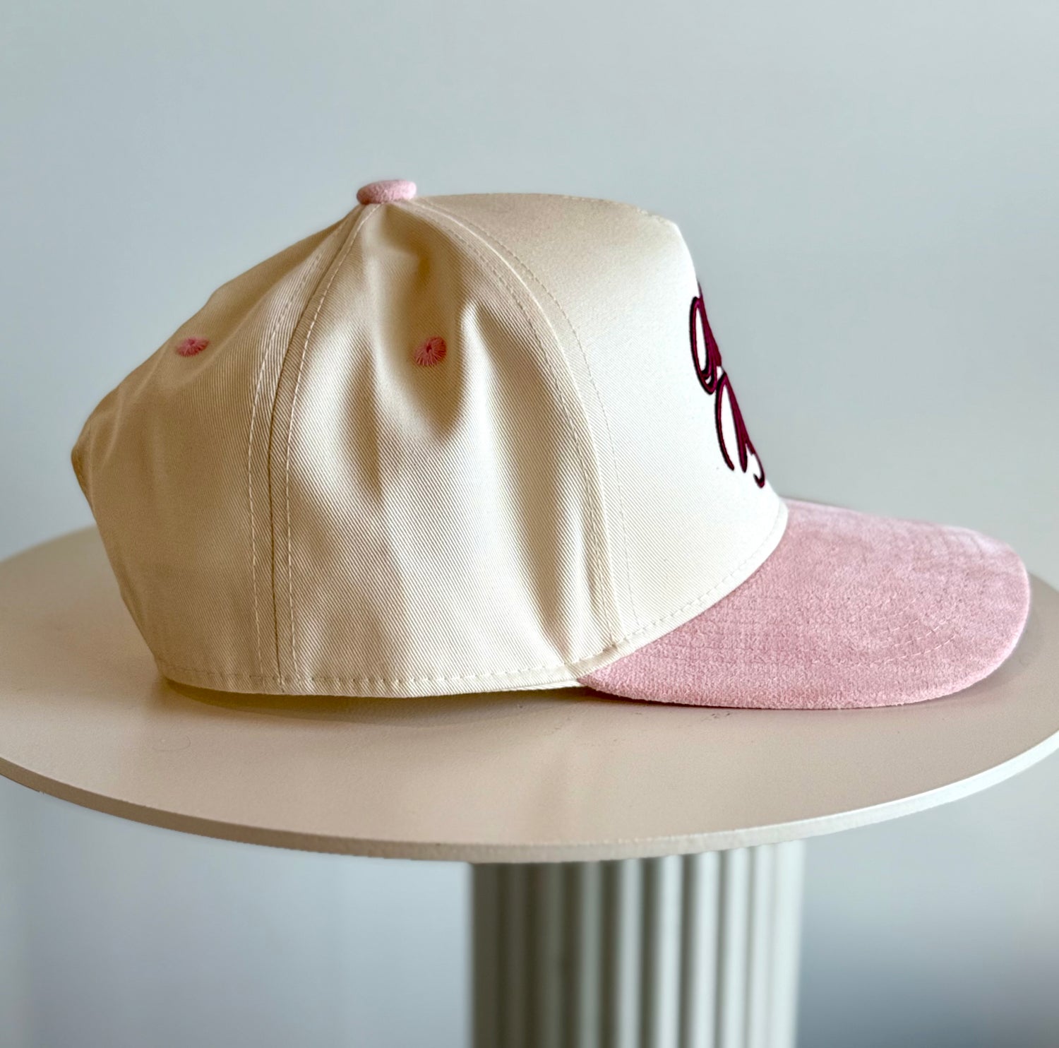 Beige and pink cap on a white surface with a light gray background
