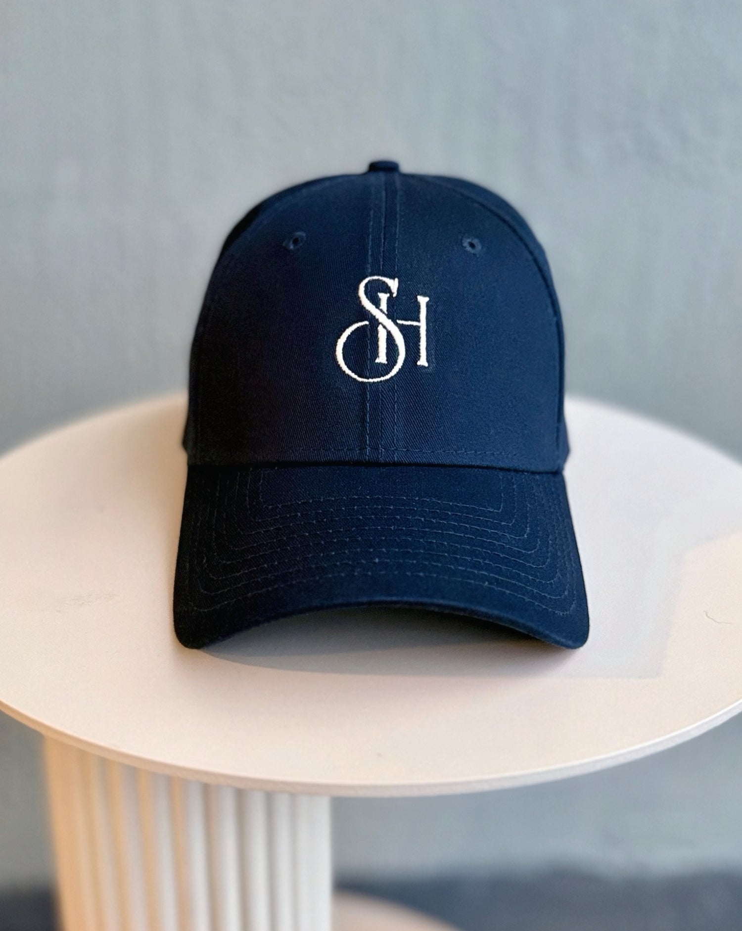 Navy blue cap with a logo on a light wooden table against a gray background