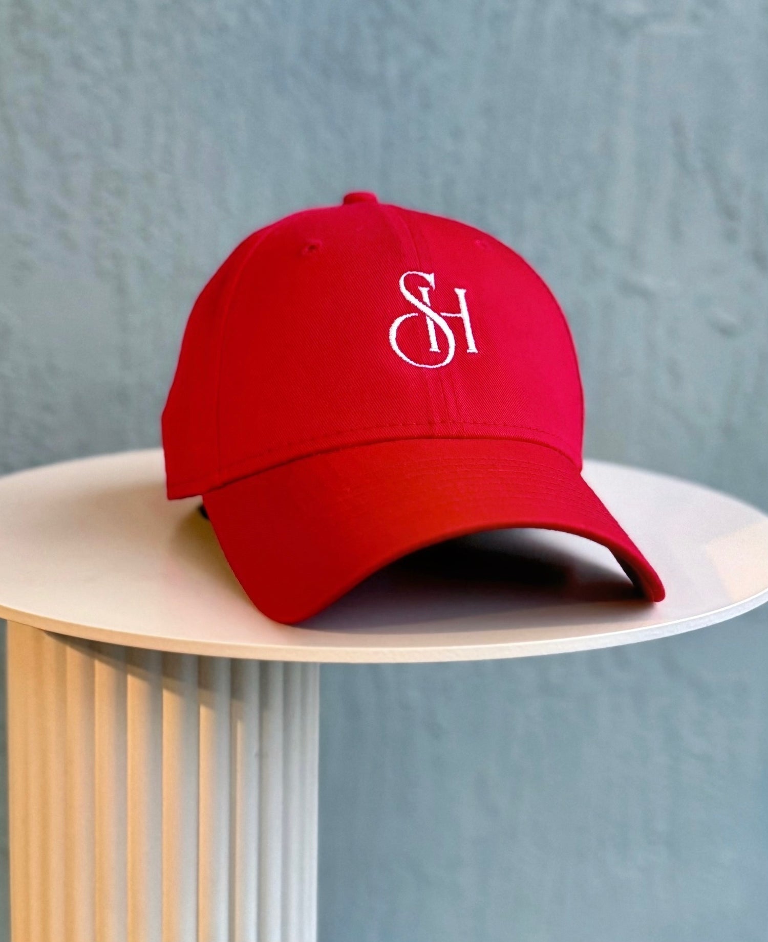 Red cap with a logo on a light wooden stand against a gray background