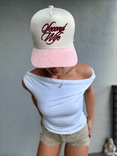 Person wearing a cap with 'Second Wife' text on a plain background