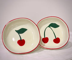 Two ceramic bowls with cherry designs on a white background