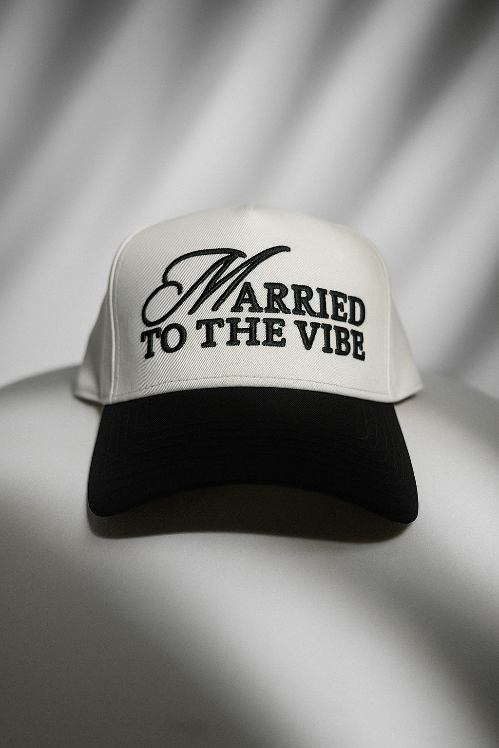 White and black cap with 'Married to the Vibe' text on a gray background