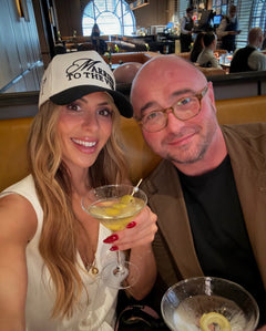 Couple in a restaurant with a woman holding a cocktail and a man wearing a sport coat