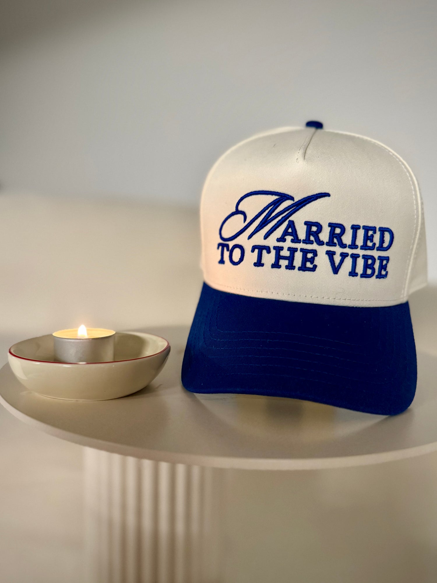 White and blue cap with 'Married to the Vibe' text on a white surface.